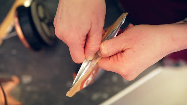 Caucasian hands open sealed foil coffee bag in slow motion