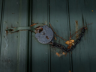 Historic rustic metal lock with chain on a green wooden door
