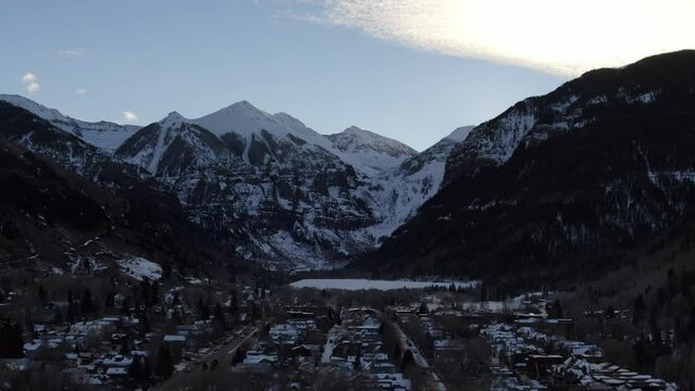 Aerial Cinematic Drone view of Telluride mountain ski resort downtown Colorado of scenic mountains landscape and historic buildings early sunrise mid winter down movement