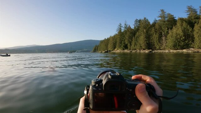 Kayaking and taking pictures with camera in Indian Arm near Belcarra, Vancouver, BC, Canada. Sunny Sunset. Adventure Travel Concept