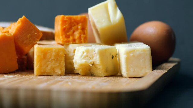 Cheese cubes green, yellow and red color on chopping board 