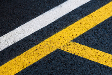 Road marking on brand new asphalt surface of a parking lot, yellow and white lines as abstract...