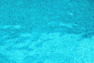 Blue ceramic tiles at the bottom of the swimming pool distorted by water ripple as background