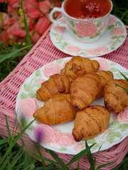 Summertime picnic setting on the grass with open picnic basket, fruit, croissants, books