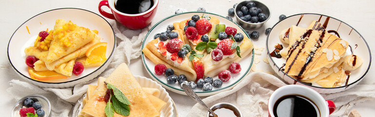 Sweet crepes assortment with berries chocolate on gray background. Homemade food concept. Top view, flat lay