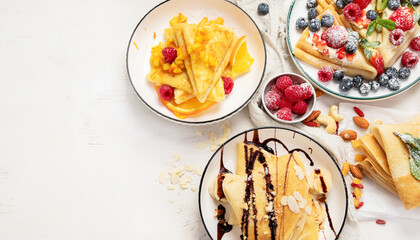 Sweet crepes assortment with berries chocolate on gray background. Homemade food concept. Top view, flat lay