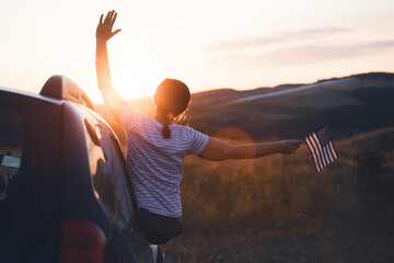 Woman in the car holding a waving american USA flag.