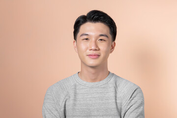 Handsome portrait of young Asian man smiling isolated on beige background