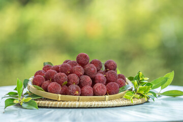 Arbutus berries Fruit or Red Yangmei in the basket under sunlight on blurred nature background.Red Bayberry, Yumberry, yamamomo, Waxberry in basket.