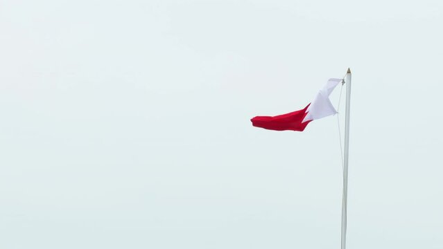Bahrain national flag cloth fabric red and white swaying on sky background. Overcast windy cloudy weather. Patriotic mood, national symbol of Bahrain country. Empty backspace