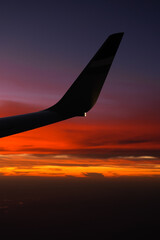 Silhouette of an airplane wing photographed against amazing sunset sky. Aviation industry transportation concept photo.