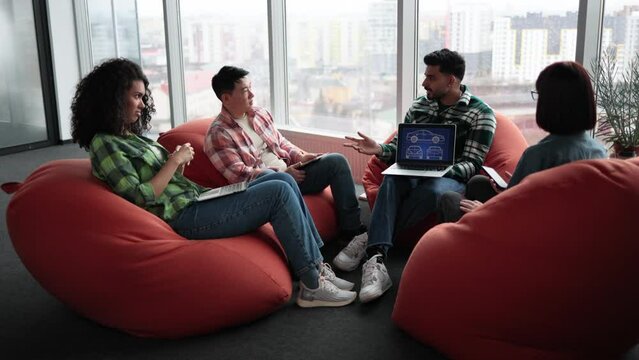 Diverse team of adults in casual clothes leveraging modern devices while working in creative office. Car designers developing digital vehicle model using computer-aided programs in meeting space.