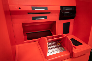 Working area of a red ATM with a keyboard, a card reader and a bill dispenser.