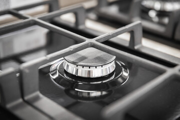 Burner of a new stylish black gas stove close-up with a cast-iron modern grate.