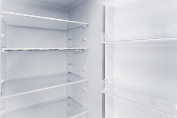 Empty white vertical new home refrigerator with shelves.