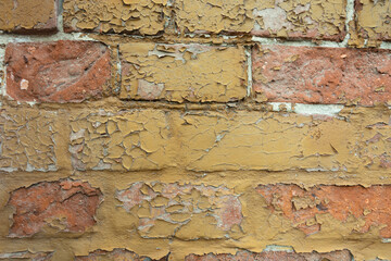 A brick wall painted with old yellow paint.