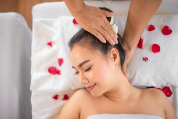 Obraz na płótnie Canvas The soft bed sprinkle with roses in the spa room added to the calming ambiance allowing the beautiful asian woman to let go of all her worries and simply enjoy the massage with professional masseuse.