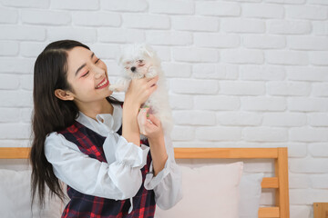 Beautiful asian woman's face with a smile as she holding the cuteness white dog her eyes sparkling with happiness and love.