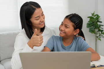 Mother teaching lesson for daughter. Asian young little girl learn at home. Do homework with kind mother help, encourage for exam.. Girl happy Homeschool. Mom advice education together.