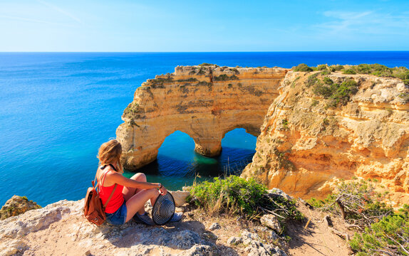 Woman tourist enjoying beautiful cave or heart shape rock formation in atlantic ocean- Algarve coast in Portugal