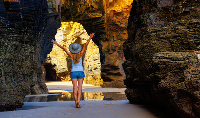 Happy woman tourist visiting famous natural rock arches on cathedral beach- Spain, Galicia