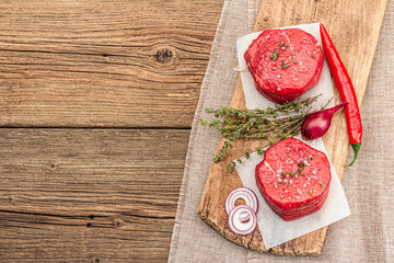 Fototapeta na wymiar Raw Eye of round steak with spices and herbs on wooden background. Fresh meat for cooking food