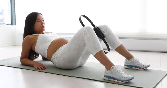 Prenatal exercises. Pregnant woman training doing pelvic exercise and thigh workout lying down on yoga mat. Portrait of expectant mother and pregnancy belly doing bodyweight training at home