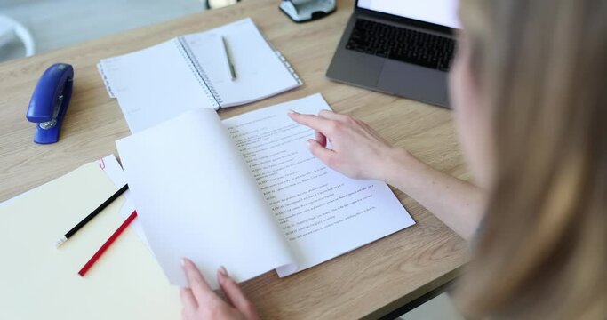 Woman hand opens scripts for filming TV show. Actress researches and reads role sitting at wooden table