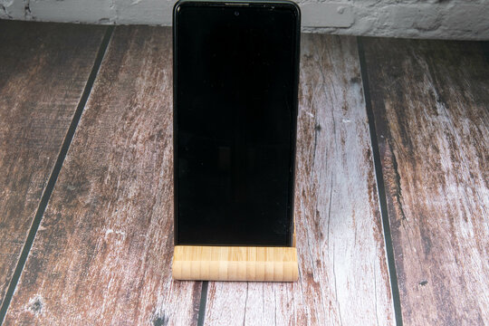 Mobile phone with dark empty Handydisplay for text free space on wooden floor for messages