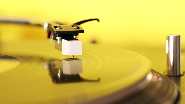 Needle of Vintage DJ Turntable Gramophone Spinning Vinyl Record on yellow