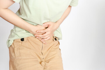 A woman in a green shirt shows abdominal pain that can be caused by gastritis, intestinal disease, cystitis or menstruation.