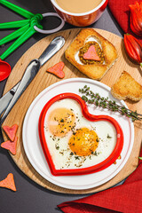 Heart-shaped fried egg served with toasted bread. Romantic art food idea for Valentine's breakfast