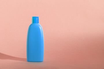 Mock up of a blue bottle with cosmetics product on a peach fuzz background. Copy space, pastel colors.