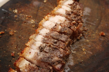 A row of sliced asian roasted pork belly on top of a wood surface