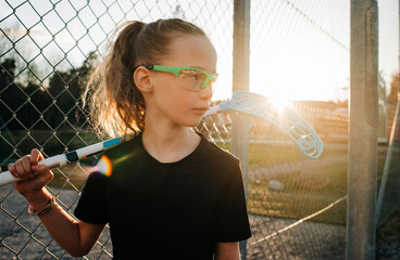 Girl holding a innebandy stick waiting to play a game at sunset