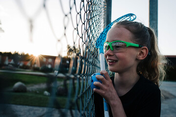 girl looking through a fence ready to plat a game of Innebandy