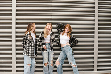 Three happy teen girls posing in front of strong vertical lines.