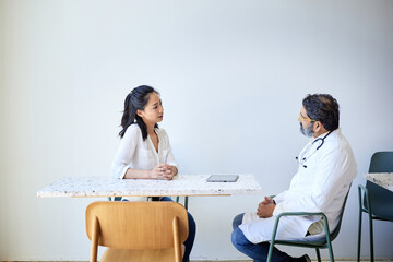 Female patient discussing with male doctor sitting on chair in clinic