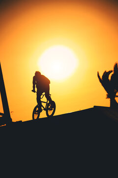 Urban athlete biker performing acrobatic jump at public park