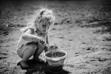 Messy child playing in sand on beach with bucket and shovel