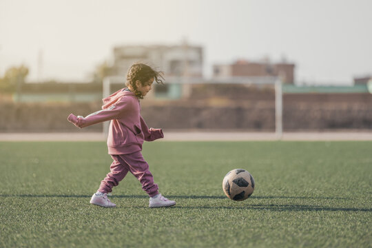 Sports kid. Happy little girl kid kicking a soccer ball, Child plays - Powered by Adobe