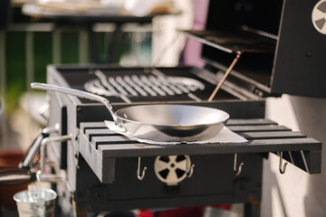 Frying pan on side stand by BBQ grill on balcony. Preparing for cook outdoor