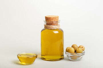 Fototapeta na wymiar Horizontal picture of olive oil in small glass bottle and whole green olives in light background.