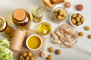 Olive oil, green whole olives in small bowls and grissini in rustic style on light background. 