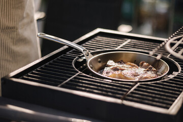 Professional outdoor grill. Close-up of male chef preparing T-bone steak on frying pan