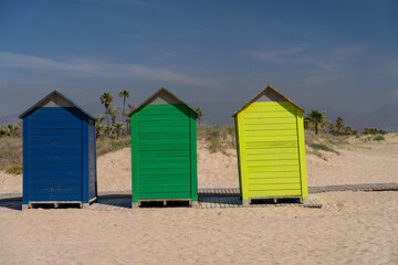 Fototapeta na wymiar The wind on the seashore in Spain in spring. Bright colourful beach houses on the sandy beach. Castellon