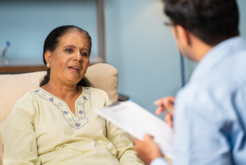Indian senior woman explaining problems to psychologist during counselling at home - concept of...