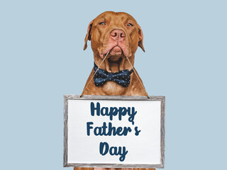 Happy Father's Day. Cute brown puppy and an inscription with words of love for Dad. Closeup, indoors. Studio photo. Congratulations for family, loved ones, friends and colleagues. Pets care concept