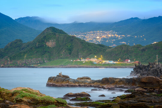 A dreamy and hazy night view of a mountain village facing the sea. Looking at the mountain city of Jiufen from Badouzi in Keelung. Taiwan