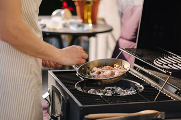 Side view of male chef preparing T-bone steak on frying pan. Classic version of cocking beef. Rosemary and butter
